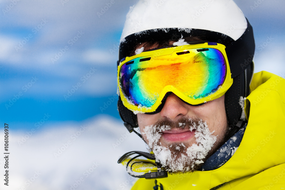 Skier man with snow on beard wear helmet and mask