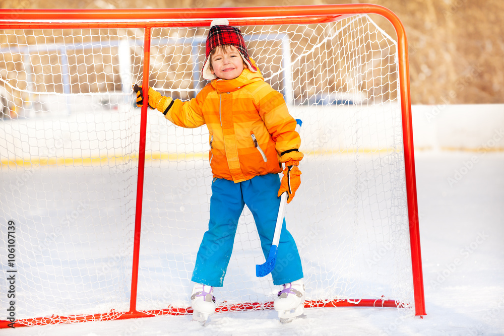 Little boy standing with hockey stick smiling