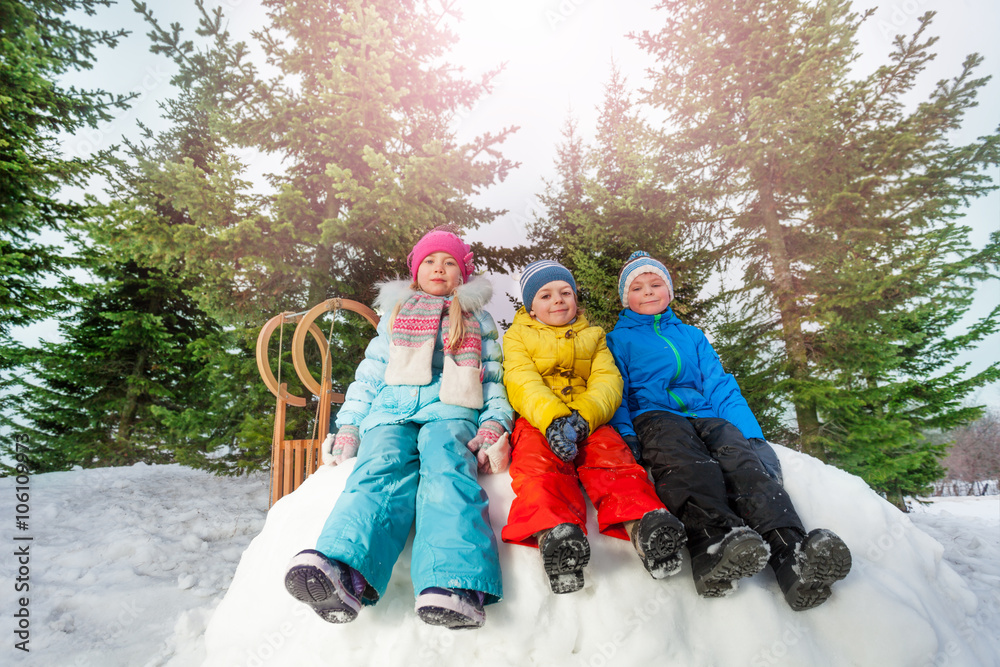 一群小孩坐在公园的雪墙上