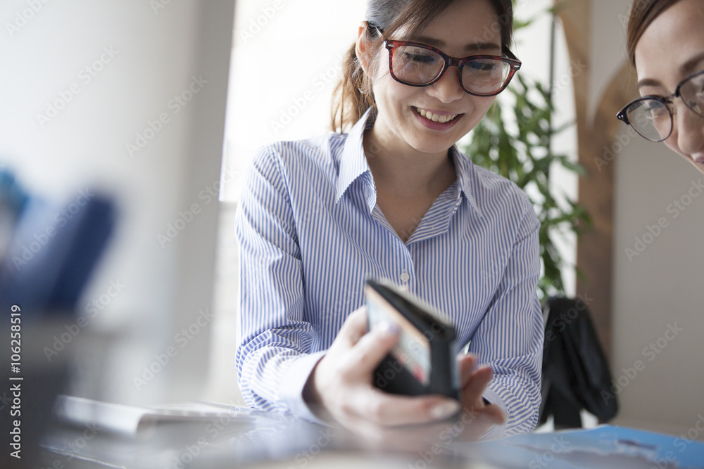 Women are talking while watching the smartphone together