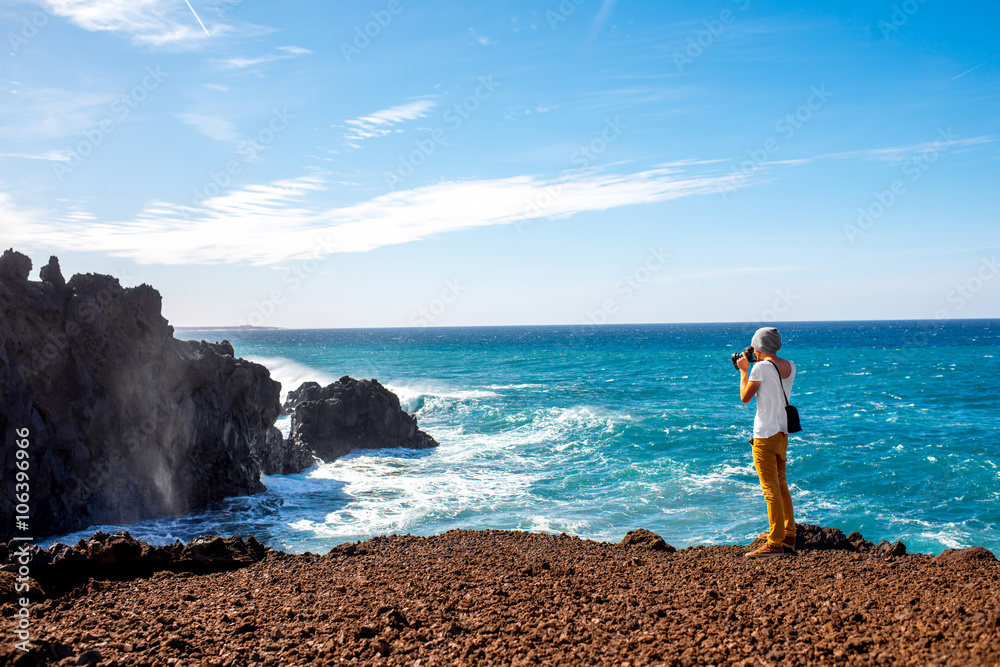 Male tourist photographing on the volcanic coast Los Hervideros on Lanzarote island in Spain