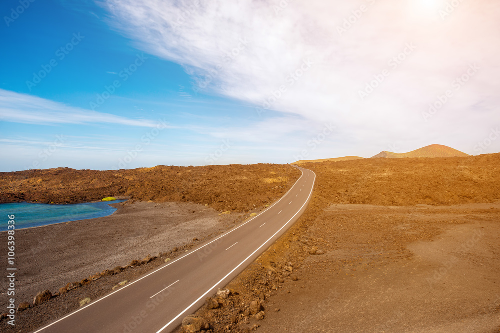 Road on the deserted landscape with natural pool on Lanzarote island in Spain