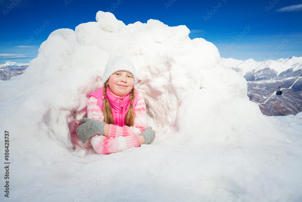 穿着粉色衣服的快乐女孩躺在雪地冰屋