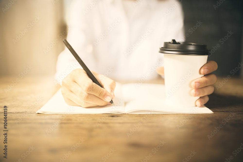 Girl writes in a diary with cup of coffee