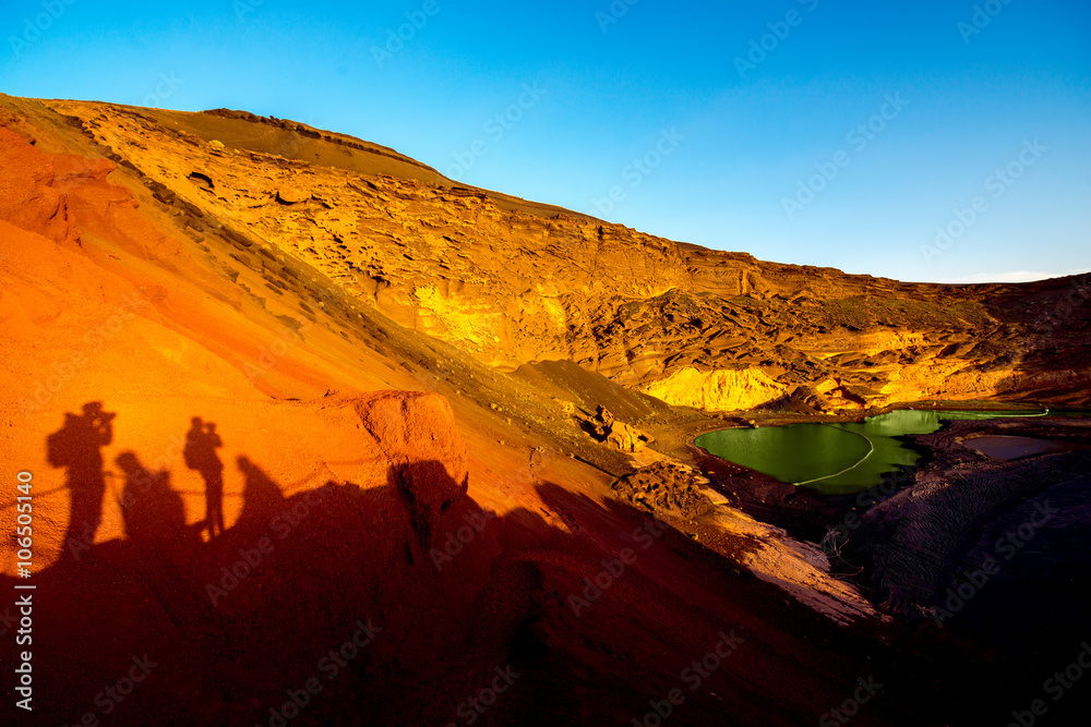 西班牙兰萨罗特岛El Golfo湾的红色火山岩与游客的阴影和绿色水池