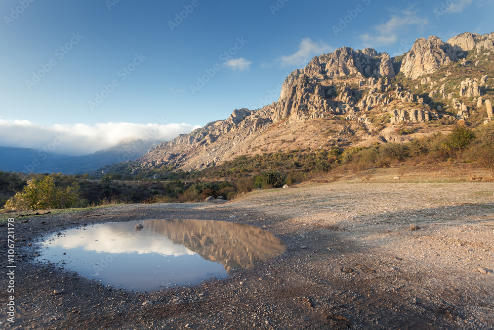 日落时，水坑中蓝天倒影的山景。