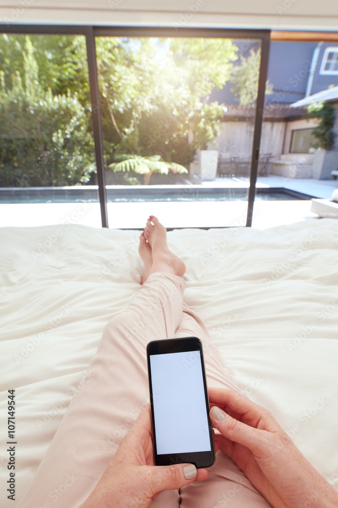 Woman with mobile phone on bed