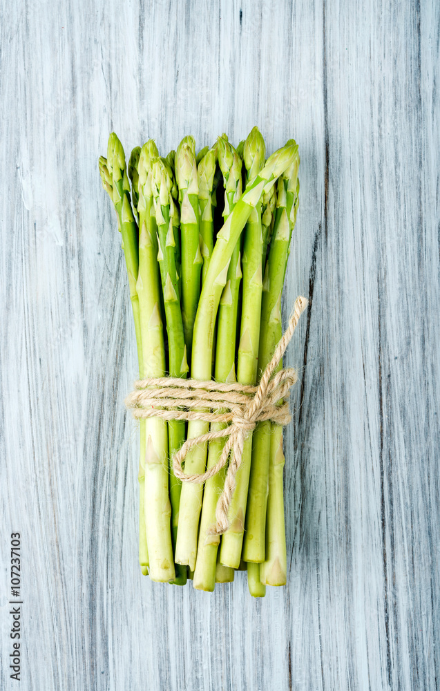 Green fresh asparagus on light painted wooden background