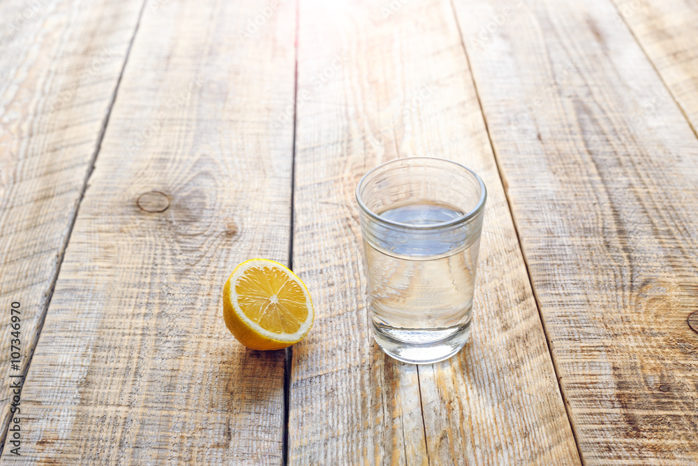 glass of fresh water with half lemon on wooden table