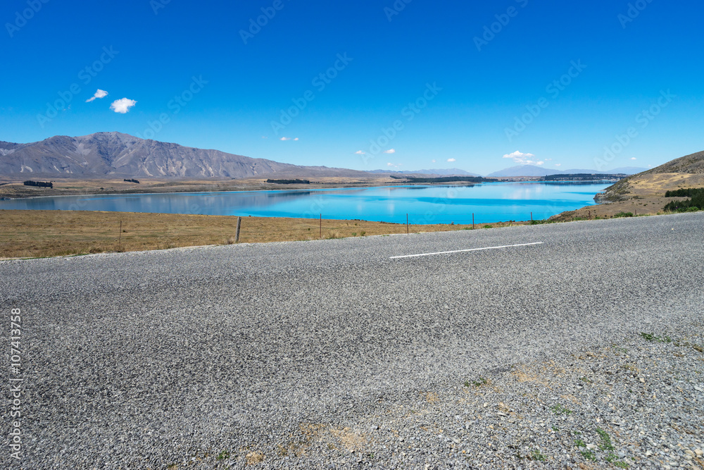 asphalt road near lake in summer day in new zealand