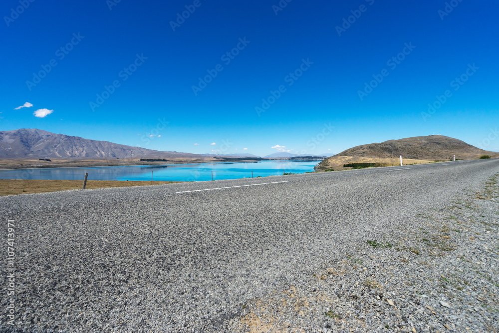 asphalt road near lake in summer day in new zealand