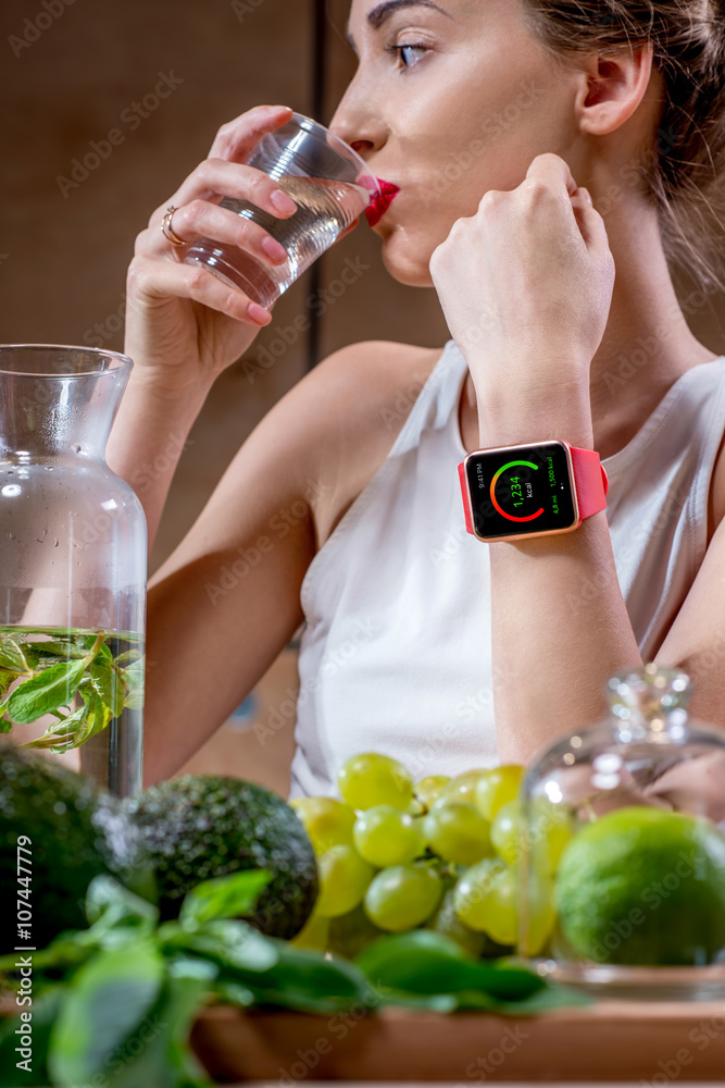 Close-up portrait of a young sport woman drinking water with smart watch showing calories and health