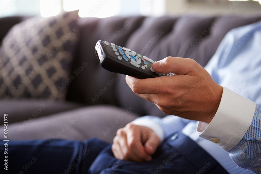 Close Up Of Man Sitting On Sofa Holding TV Remote