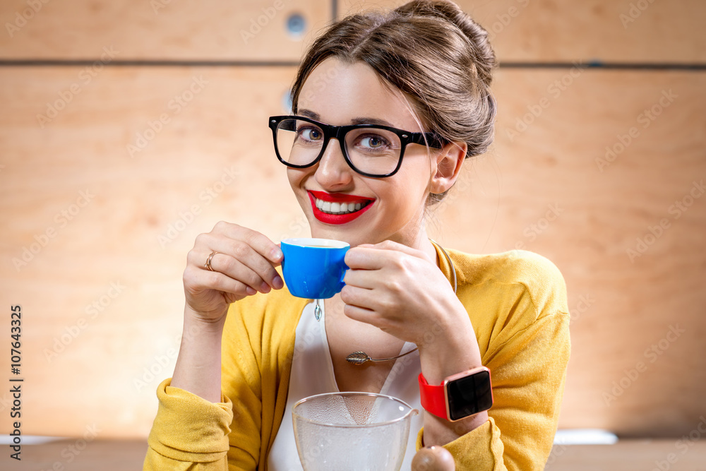 Young woman drinking coffee from the blue cup on the wooden background