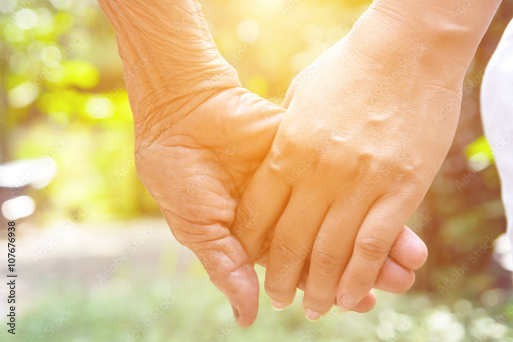 Senior and young holding hands