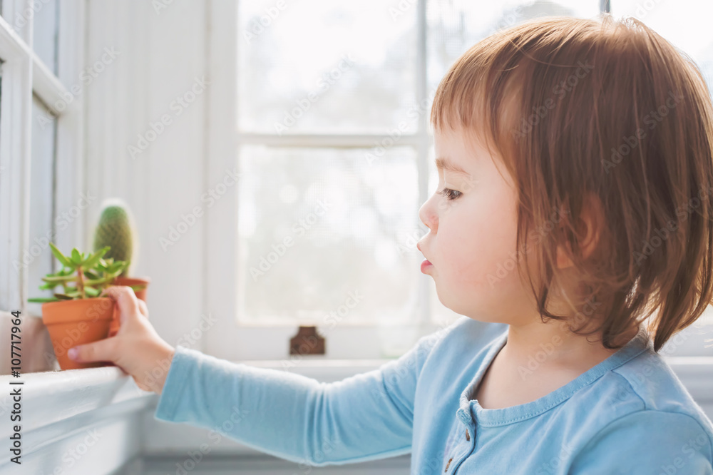  Happy toddler girl playing with potted plants