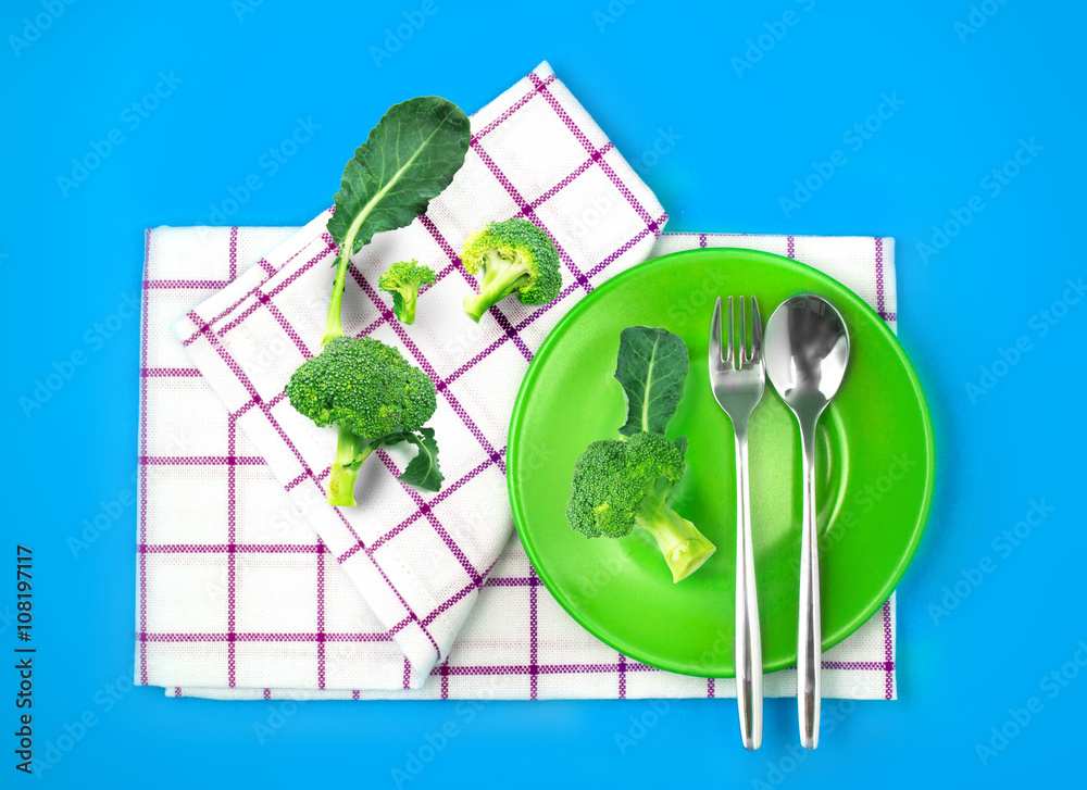 top view of fresh broccoli in green dish and towel on vibrant