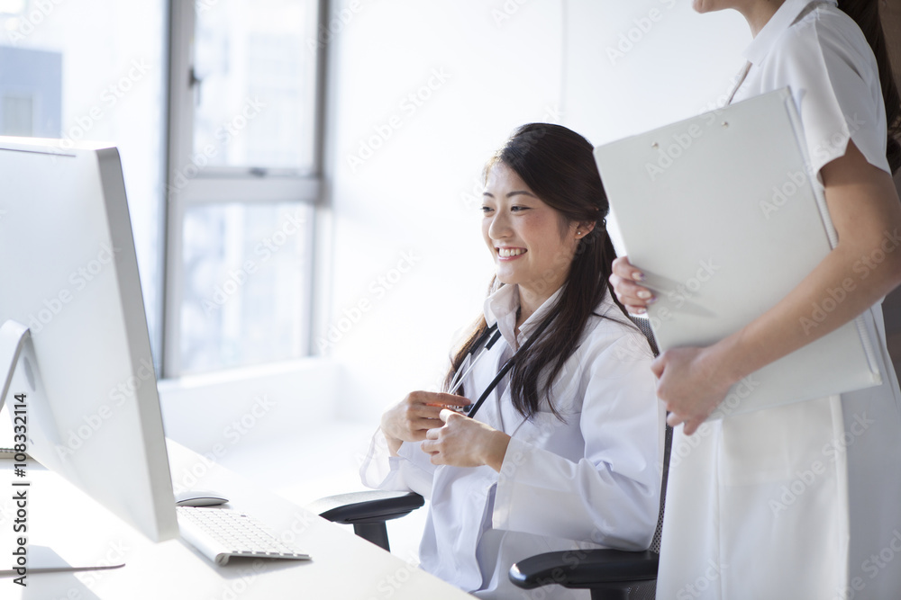 女医生和护士正在看着个人电脑的屏幕