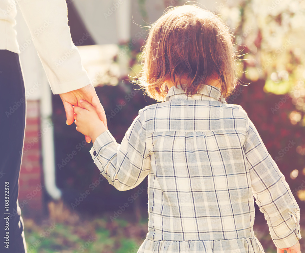 Toddler girl holding hands with her mother