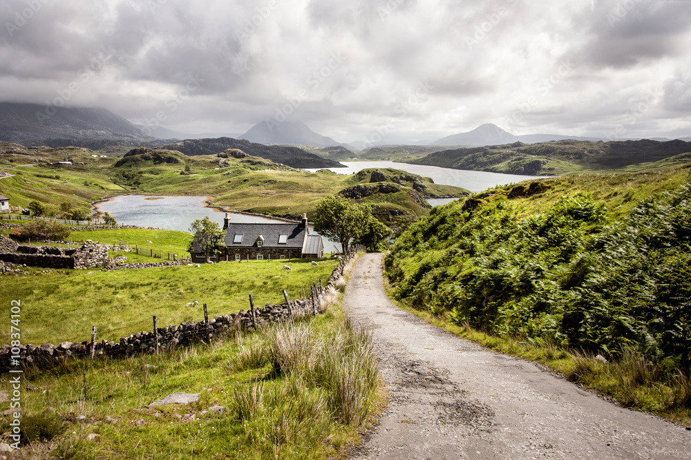 Highlands, Scotland: Scenic spot with narrow road, fields, house, lakes and mountains in the backgro