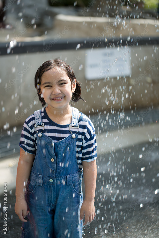 Asian girl playing with water fountain at water park