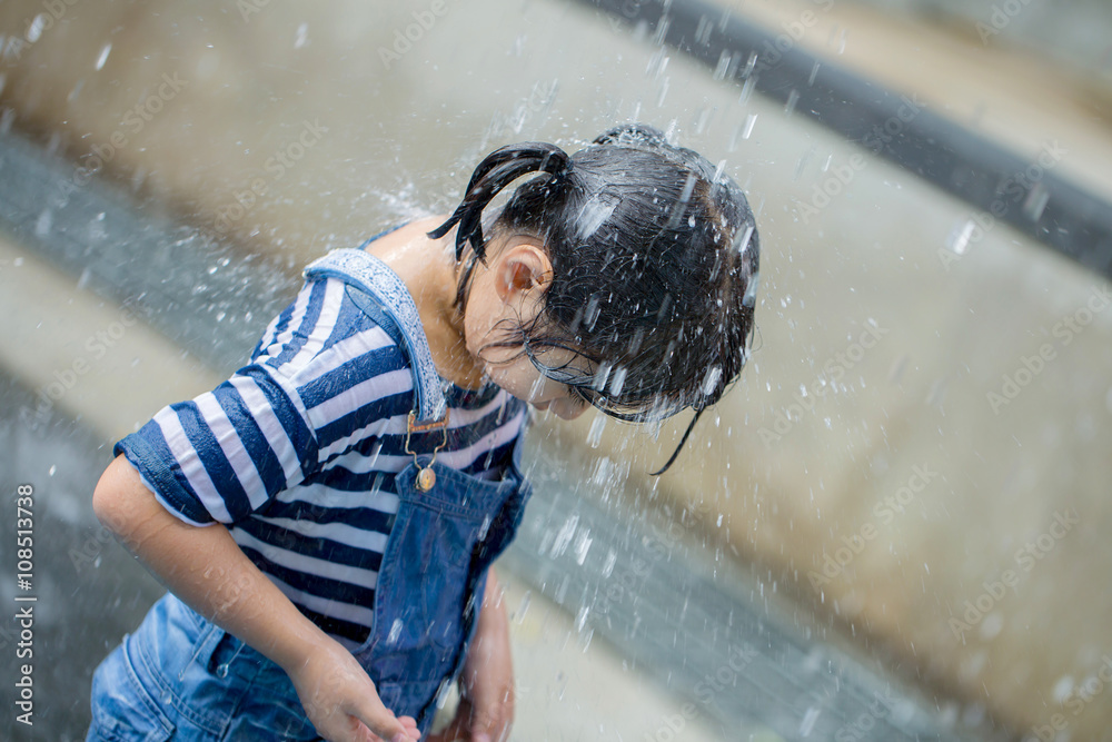 Asian girl playing with water fountain at water park