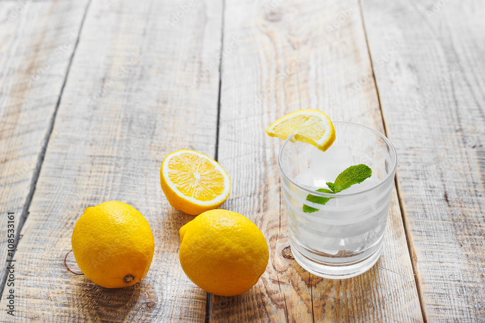 glass of lemonade with  lemons on wooden table