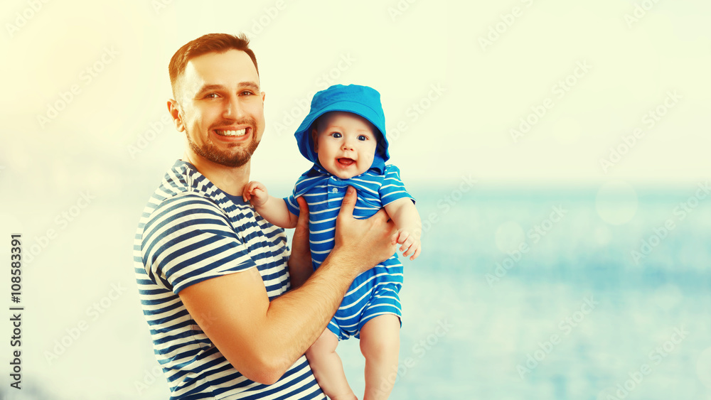 happy family father and baby son on beach by sea at sunset