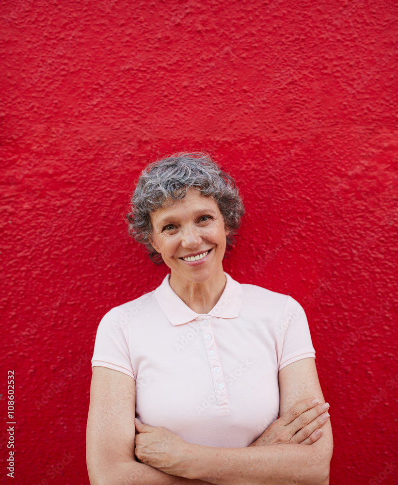 Happy senior woman standing against red background