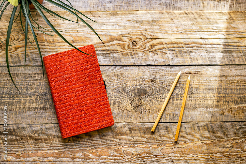 orange notebook with green flower on wooden table