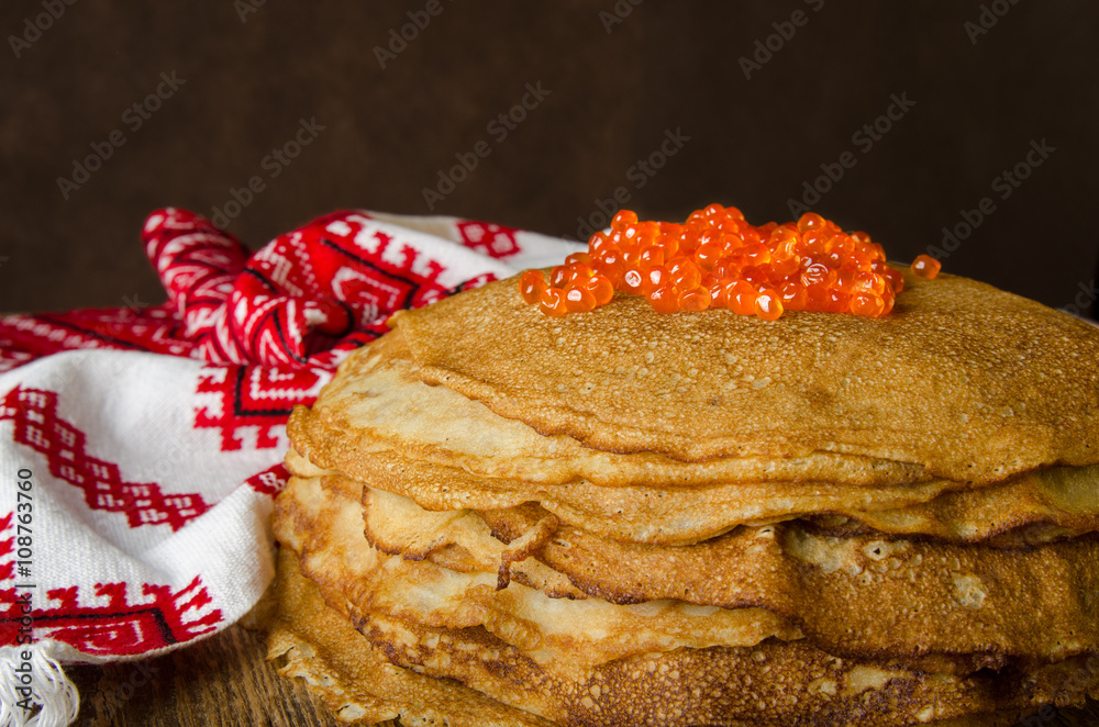 传统俄罗斯煎饼配红色鱼子酱，木质乡村背景。Maslenitsa。