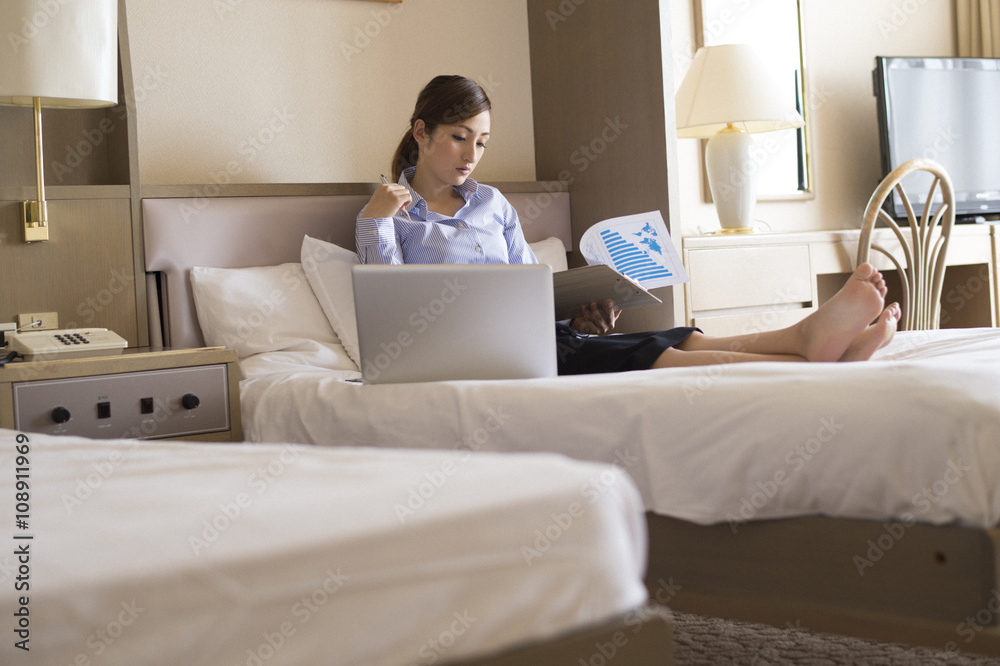 Women sat on the bed of a business  hotel, has been working with a laptop