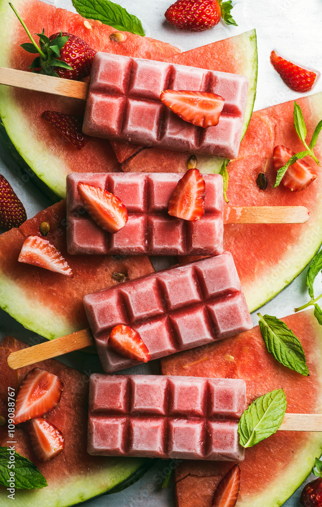 Strawberry watermelon ice cream popsicles with mint over steel tray background