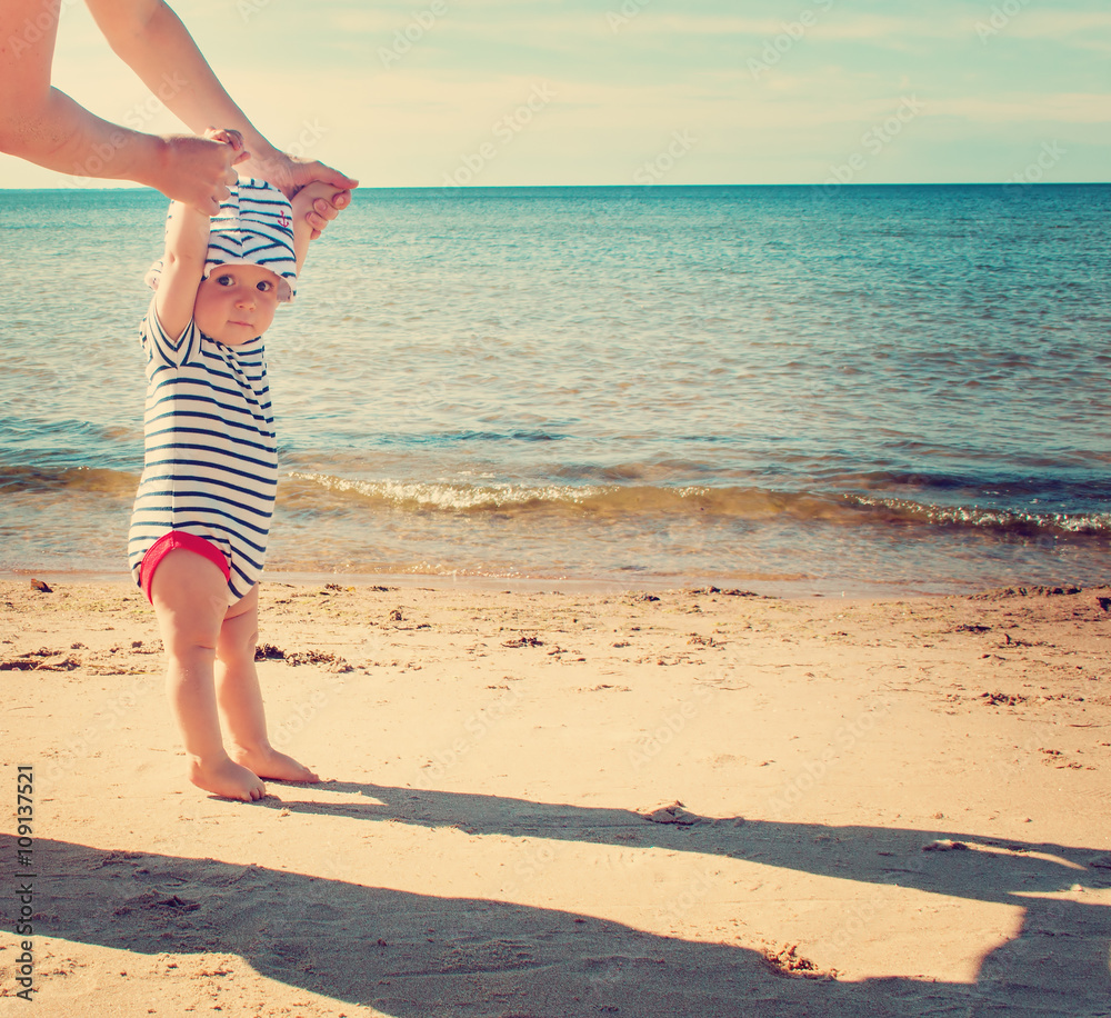 Little baby boy walking on the beach in summer day