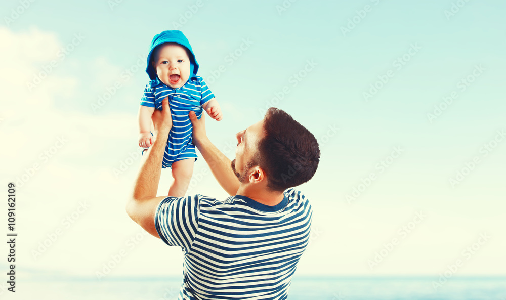 happy family father and baby son on beach by sea at sunset