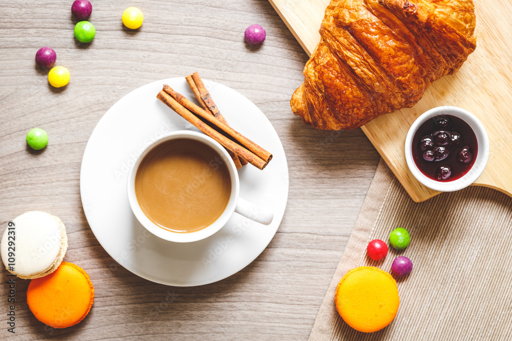 sweet breakfast with coffee, macaroons and croissants on wooden table