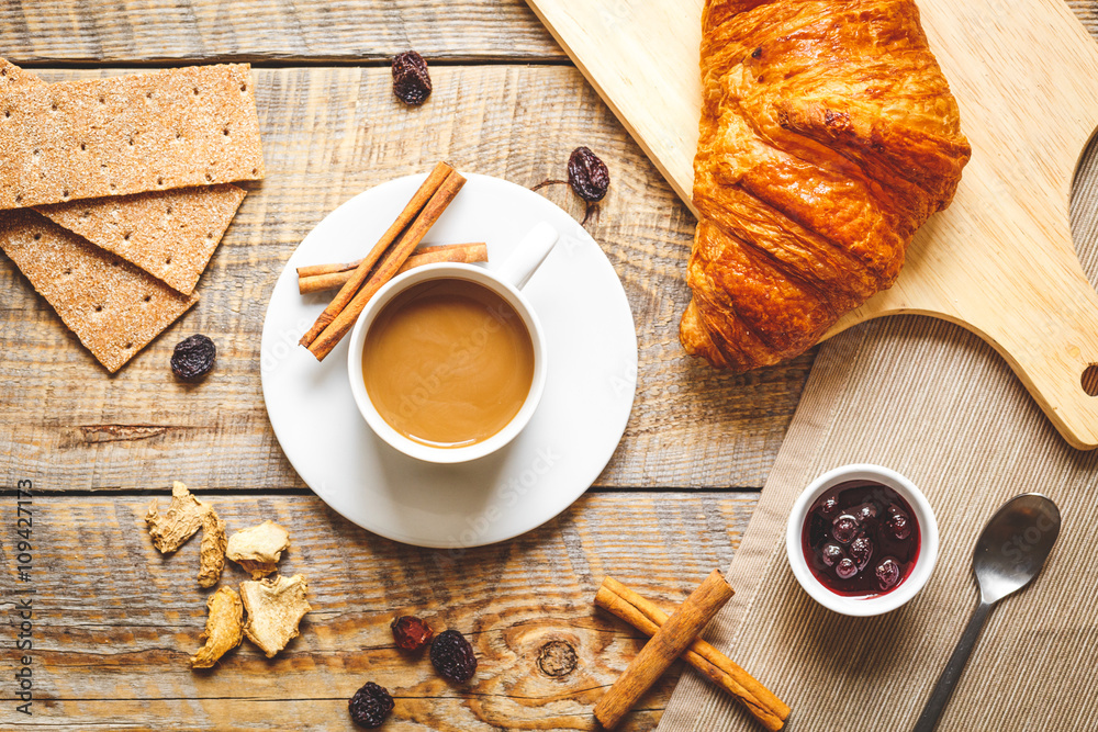 Breakfast with coffee, crackers and croissants on wooden table