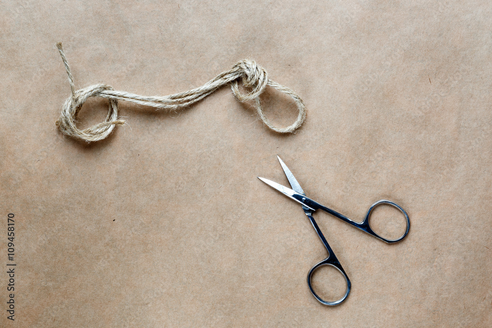 scissors cut the knot on rope at background kraft paper