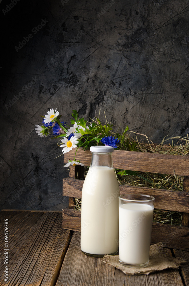 A bottle of rustic milk and glass of milk on a wooden table