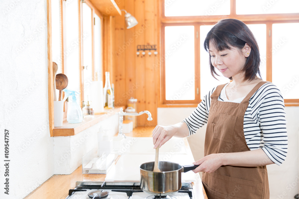 迷人的亚洲女人在ktichen烹饪