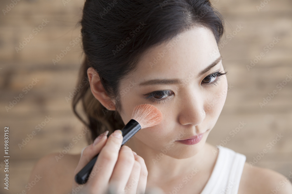 Young women are painted teak while looking in the mirror