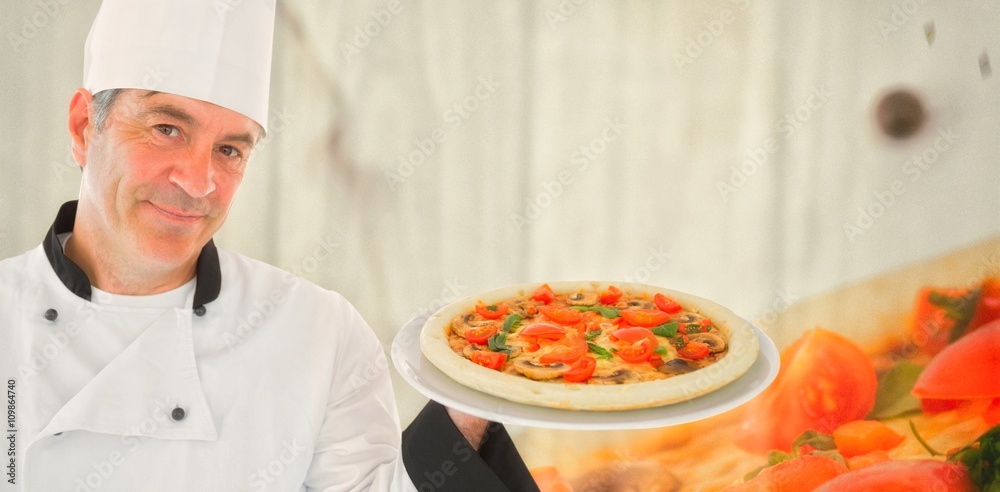 Composite image of friendly chef holding a pizza