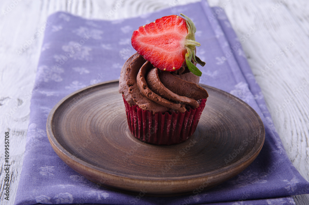 Chocolate cupcakes with strawberry on a wooden table.