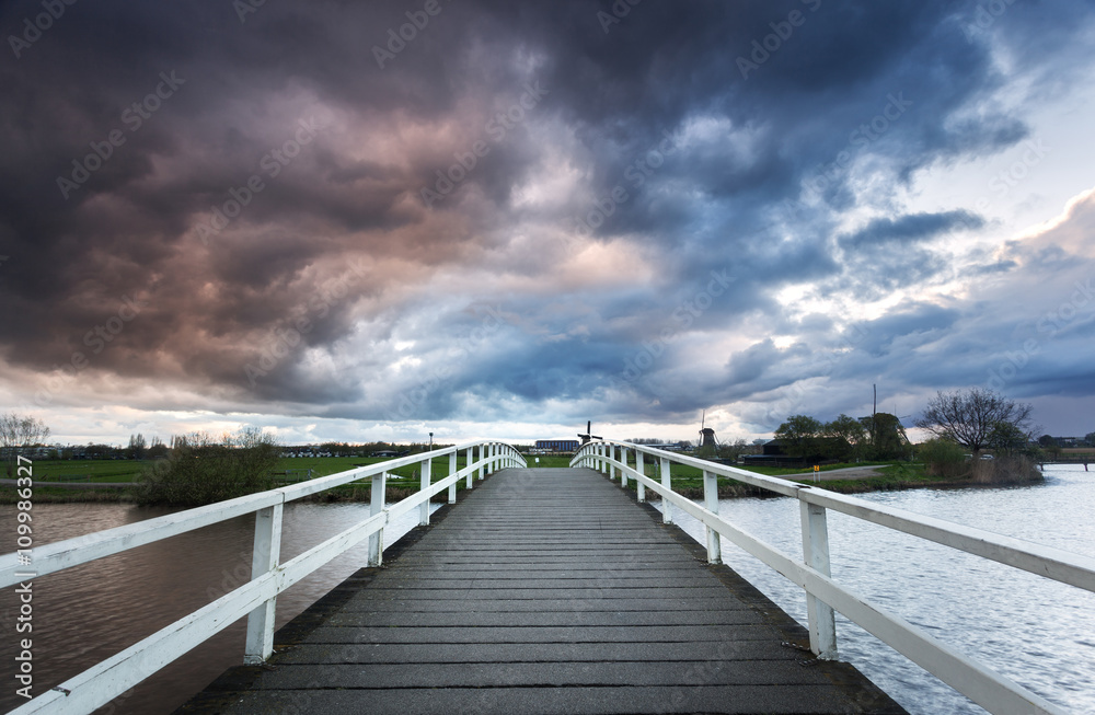 美丽的木桥，背景是著名的Kinderdijk，Net日落时戏剧性的多云天空