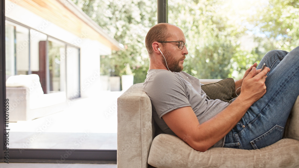 Man relaxing on sofa using digital tablet