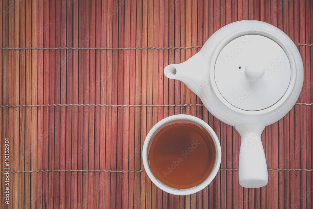 Cup of hot chinese tea and tea pot on bamboo mat plate