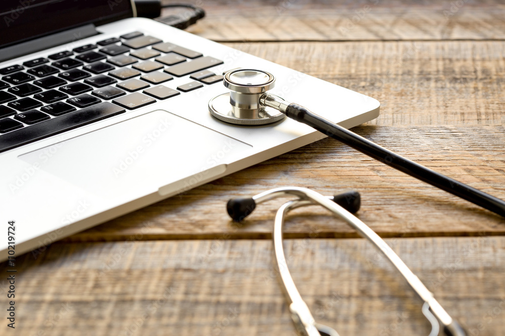 doctor workplace with a stethoscope and laptop at wooden table