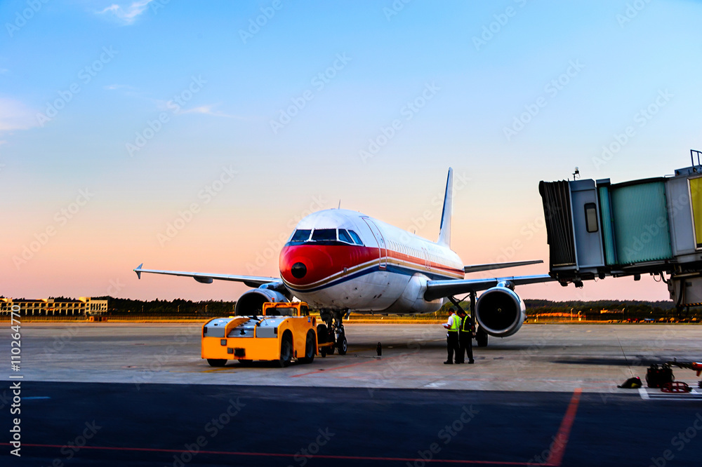 Airplane near the terminal in an airport at the sunset