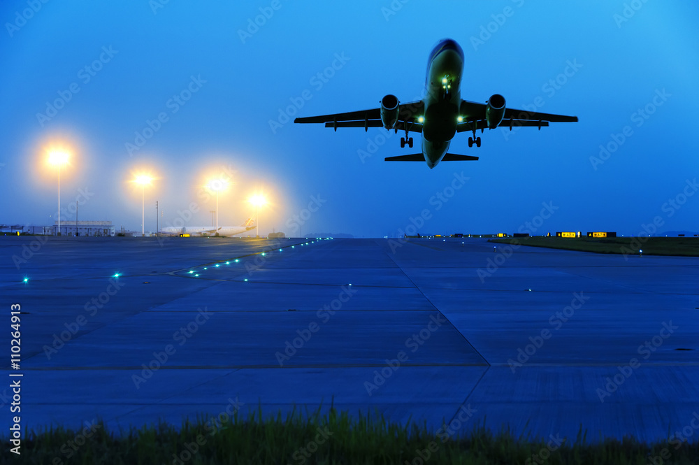 passenger plane fly up over take-off runway from airport at sunset