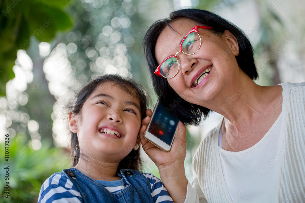 Little Asian girl calling mobile phone with her grandmother